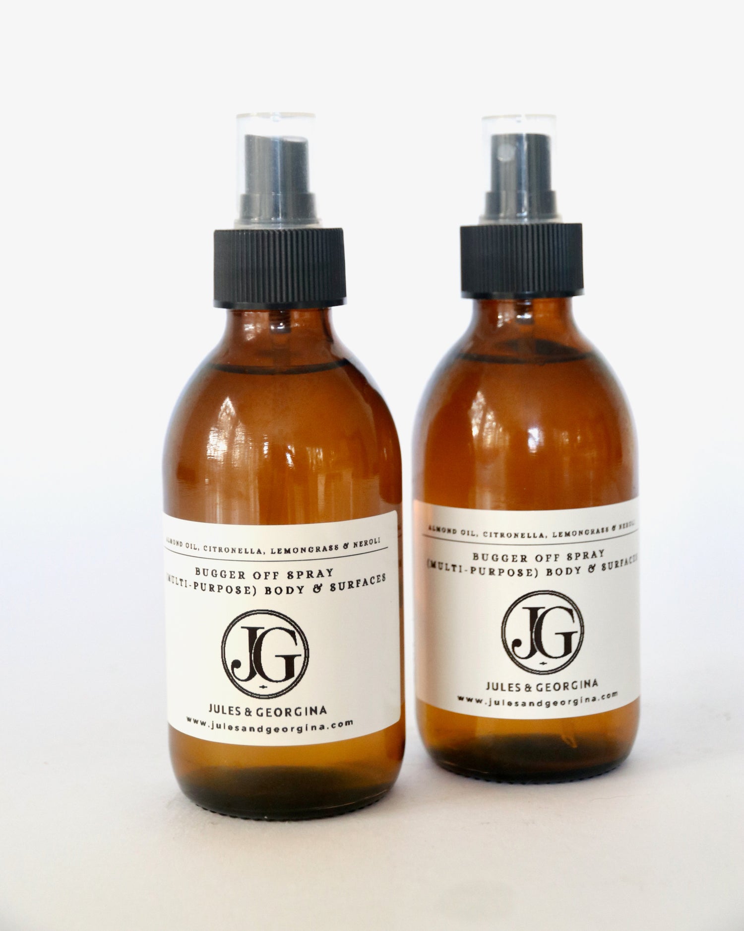 Two brown spray bottles with black nozzles and white labels on a white background